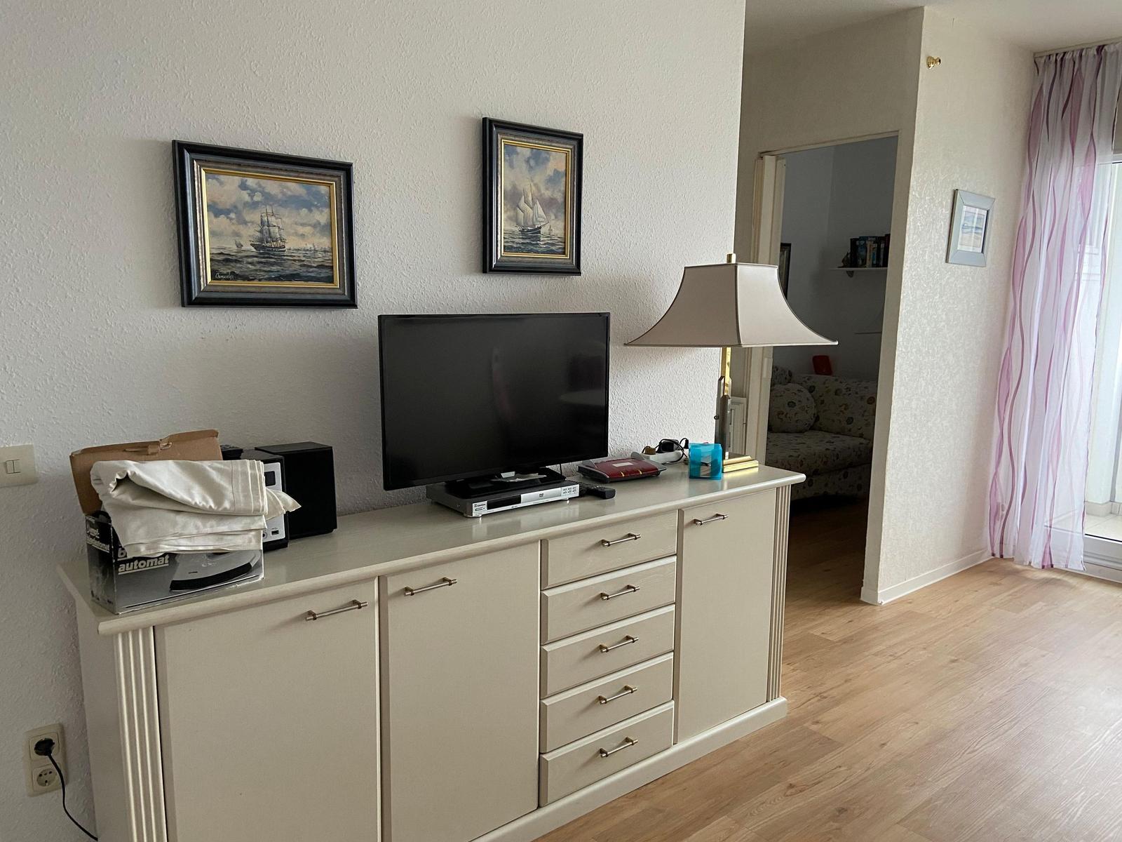 TV-Schrank mit Fernseher, Bildern und Lampe. Blick in das Wohnzimmer.