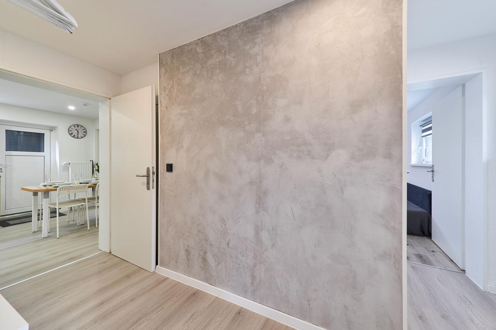 Raum mit großer Wand, Tür zur Küche und Schlafzimmeransicht.