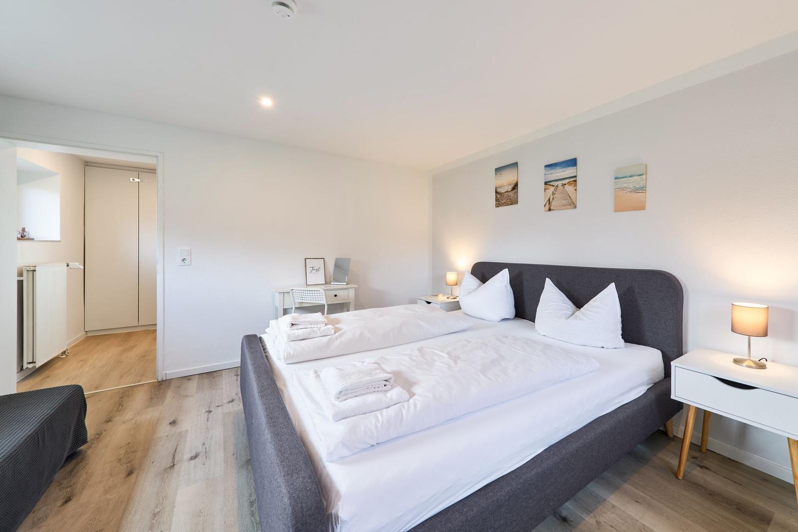 Schlafzimmer mit Doppelbett, Nachttischen und Wandbildern.