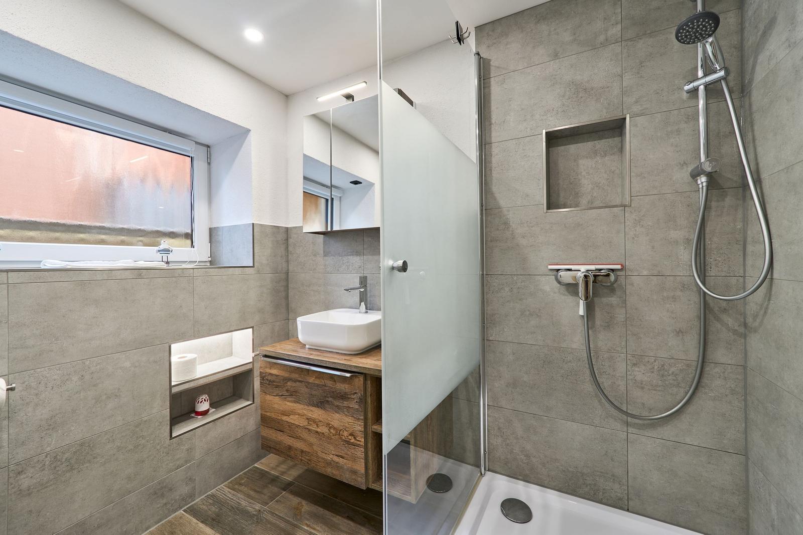 Badezimmer mit Dusche, Waschbecken und Fenster