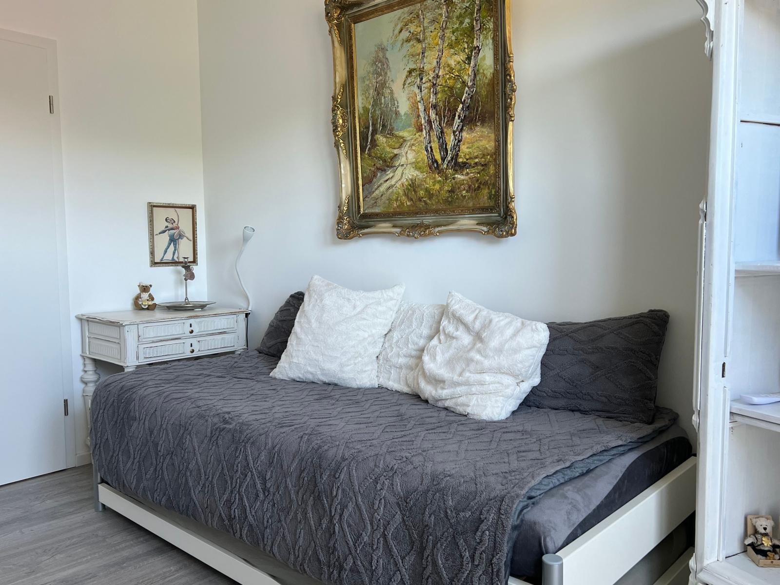 Schlafzimmer mit Bett, Nachttisch und Wandbild
