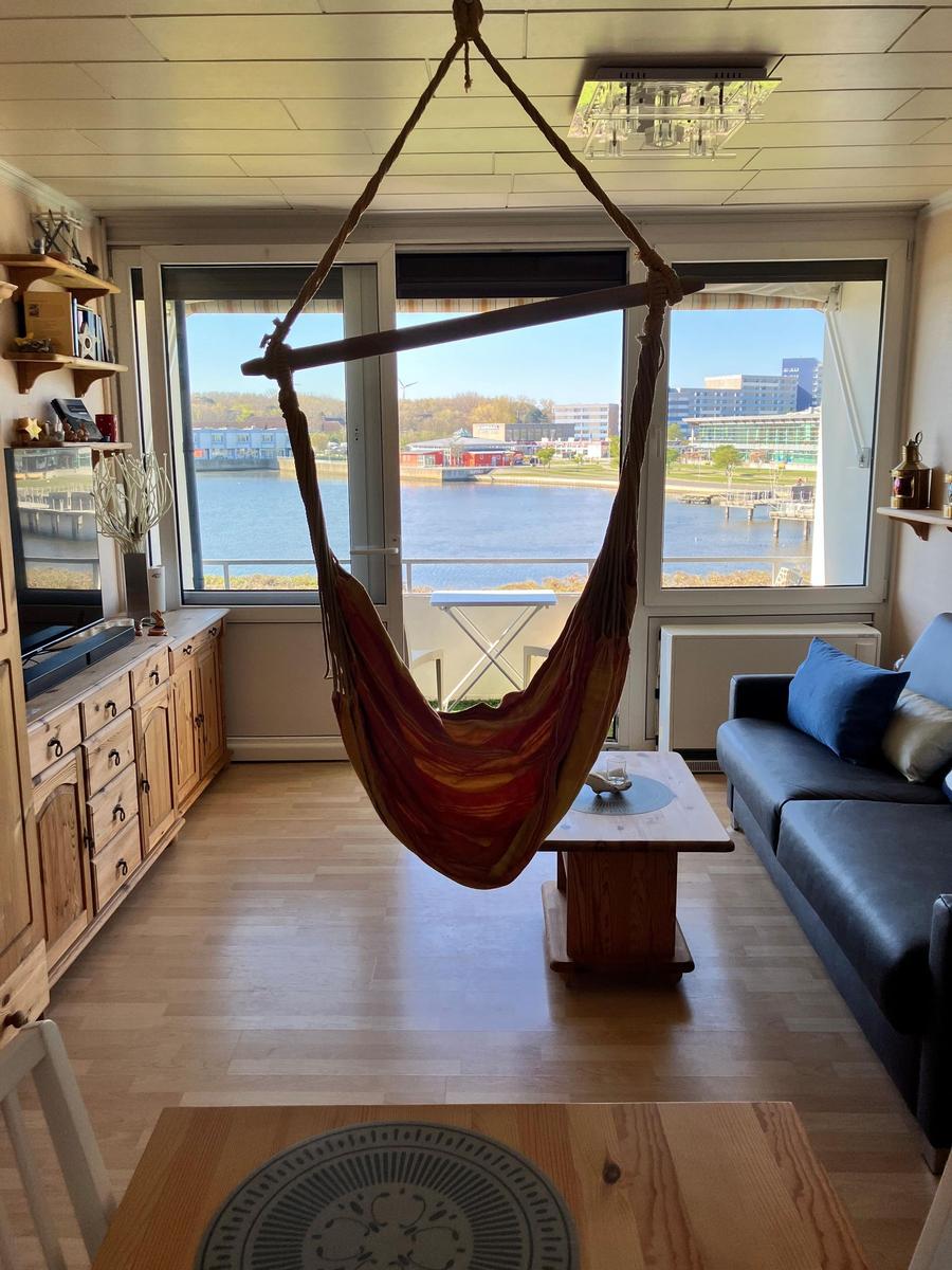 Wohnraum mit Hängematte, Sofa und Blick auf Wasser.