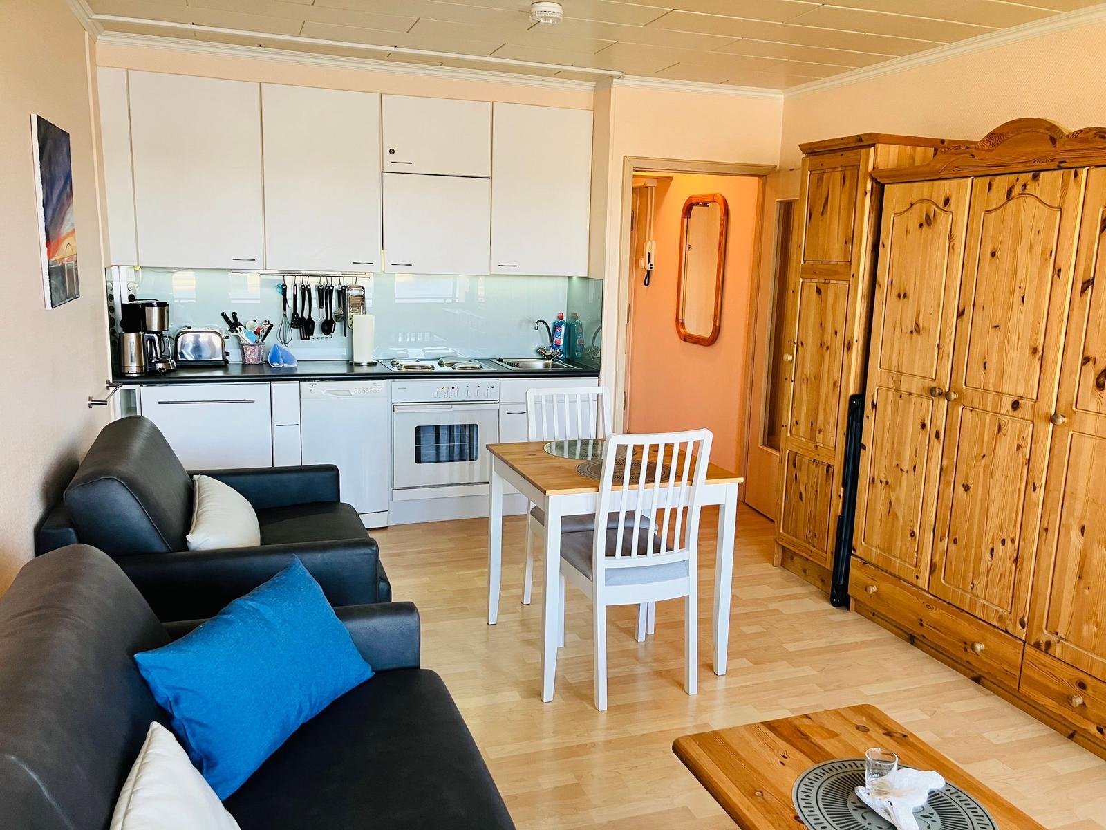 Wohnküche mit Sofa, Esstisch und Holzschrank.