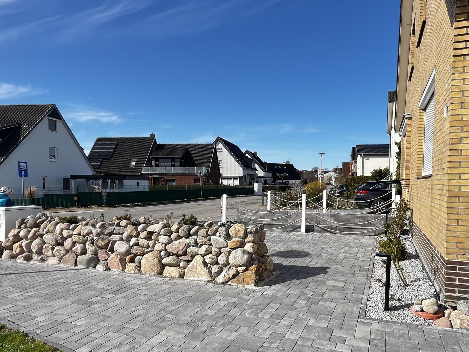 Pflasterter Hof mit Steinmauer und gepflastertem Weg zu einem Haus.