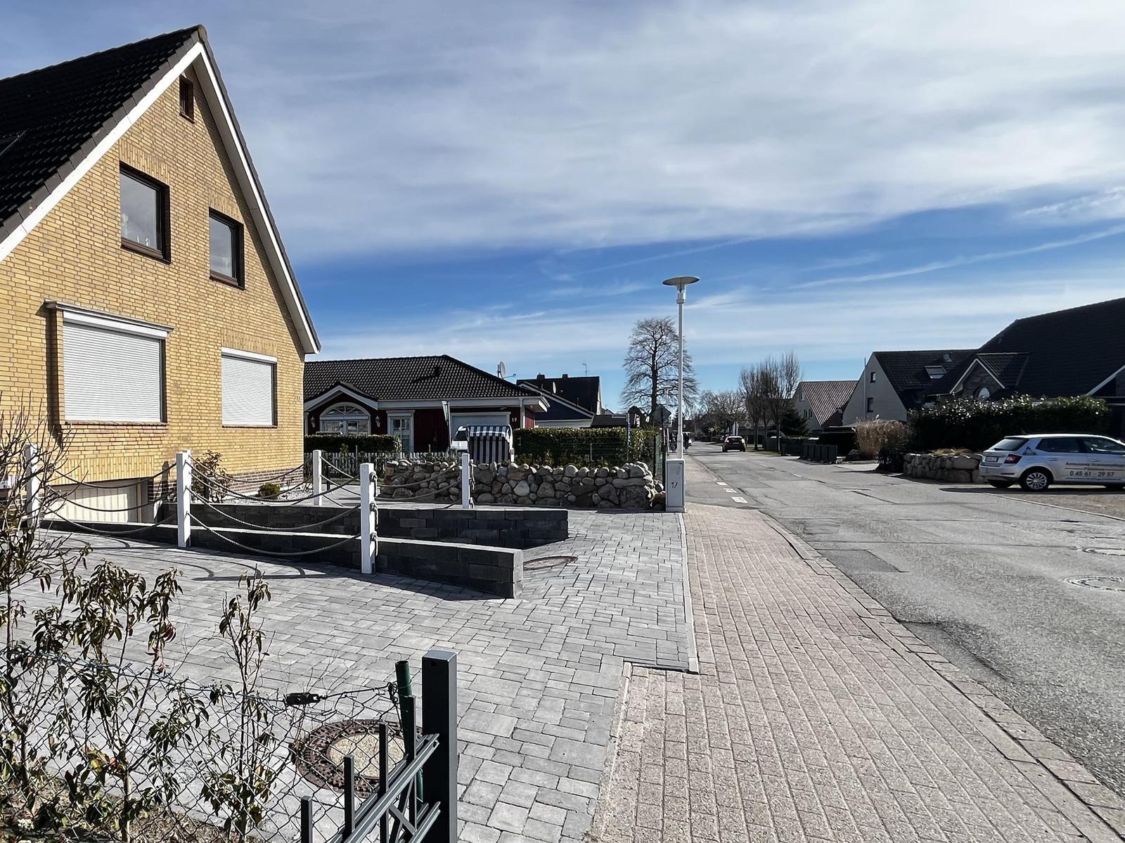 Haus mit gepflastertem Vorplatz und Straße im Hintergrund.