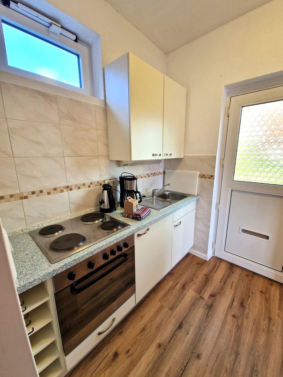 Küche mit Kochfeld, Backofen, Spüle und Fenster