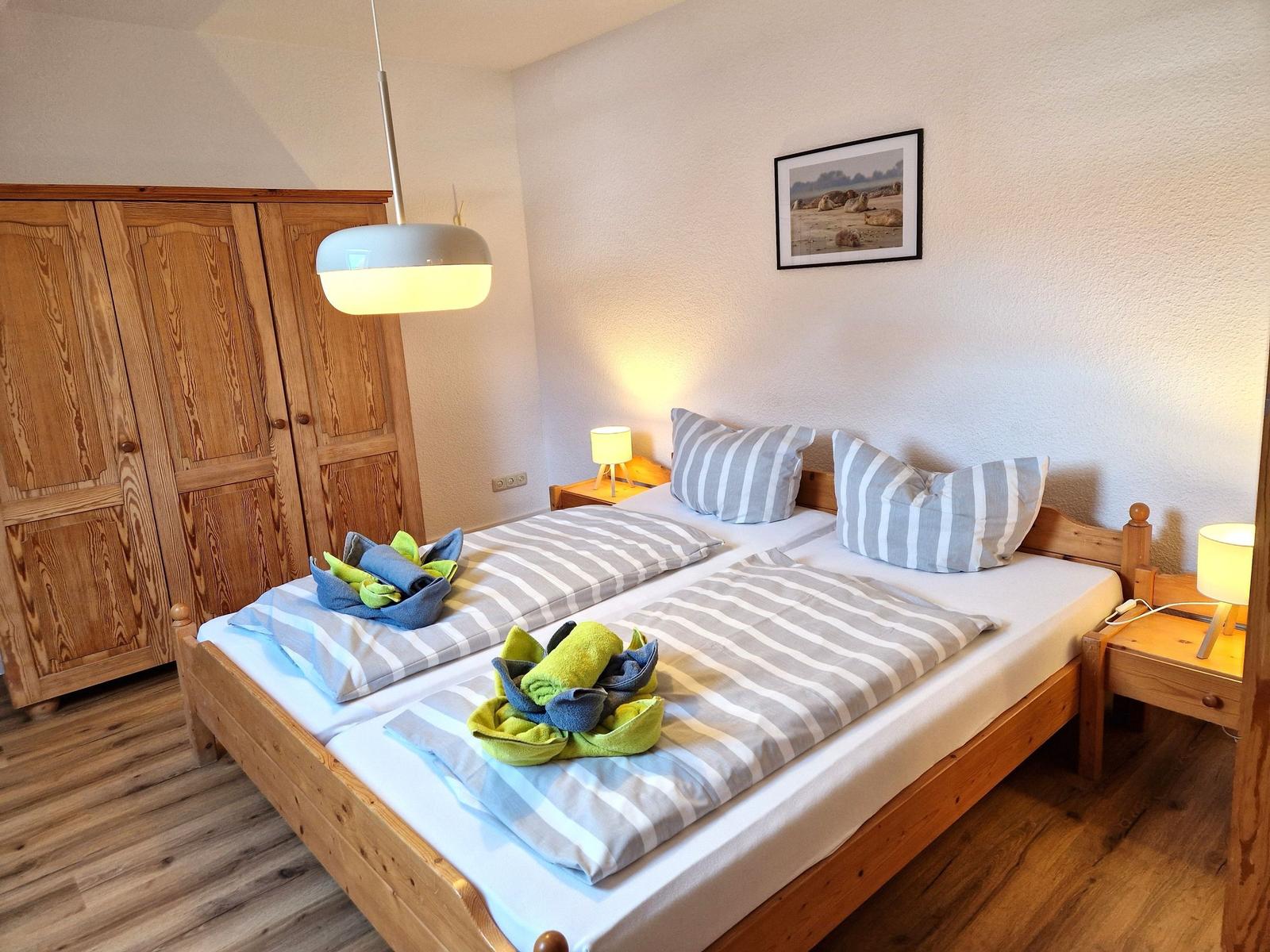 Double bed with striped bedding, wooden furniture, and nightstands with lamps.