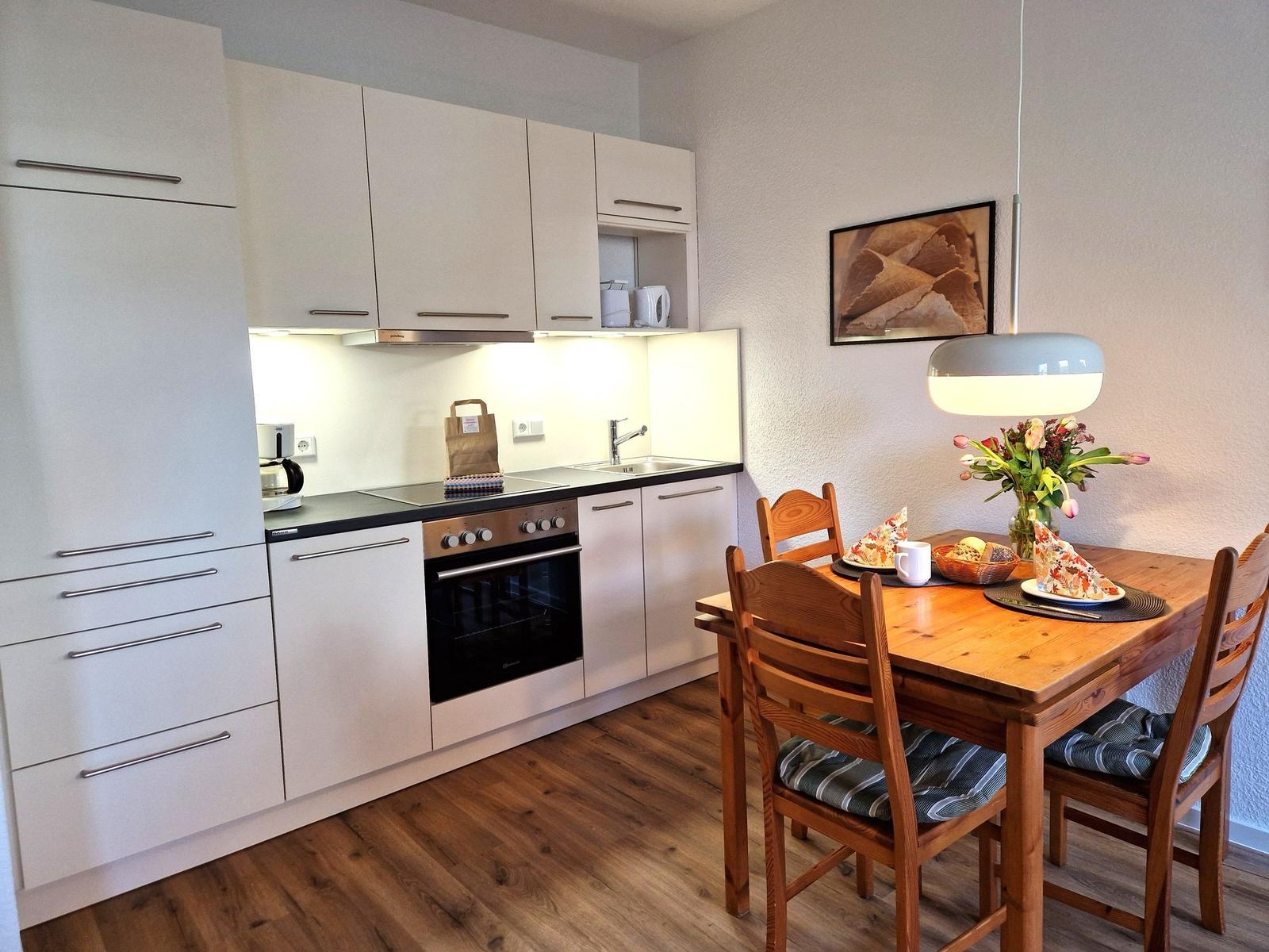 Kitchen with dining area, wooden table, chairs, and kitchenette with stainless steel stove.