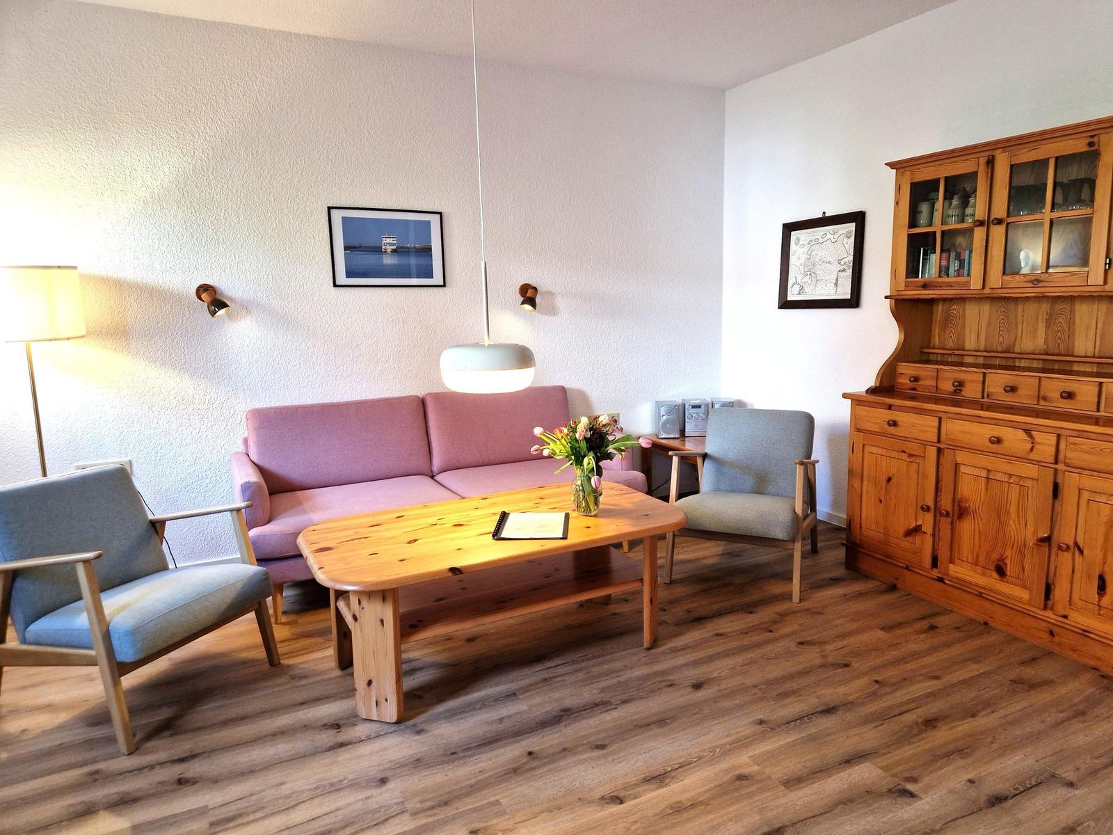Living room with pink sofa, wooden table, and wooden cabinet.