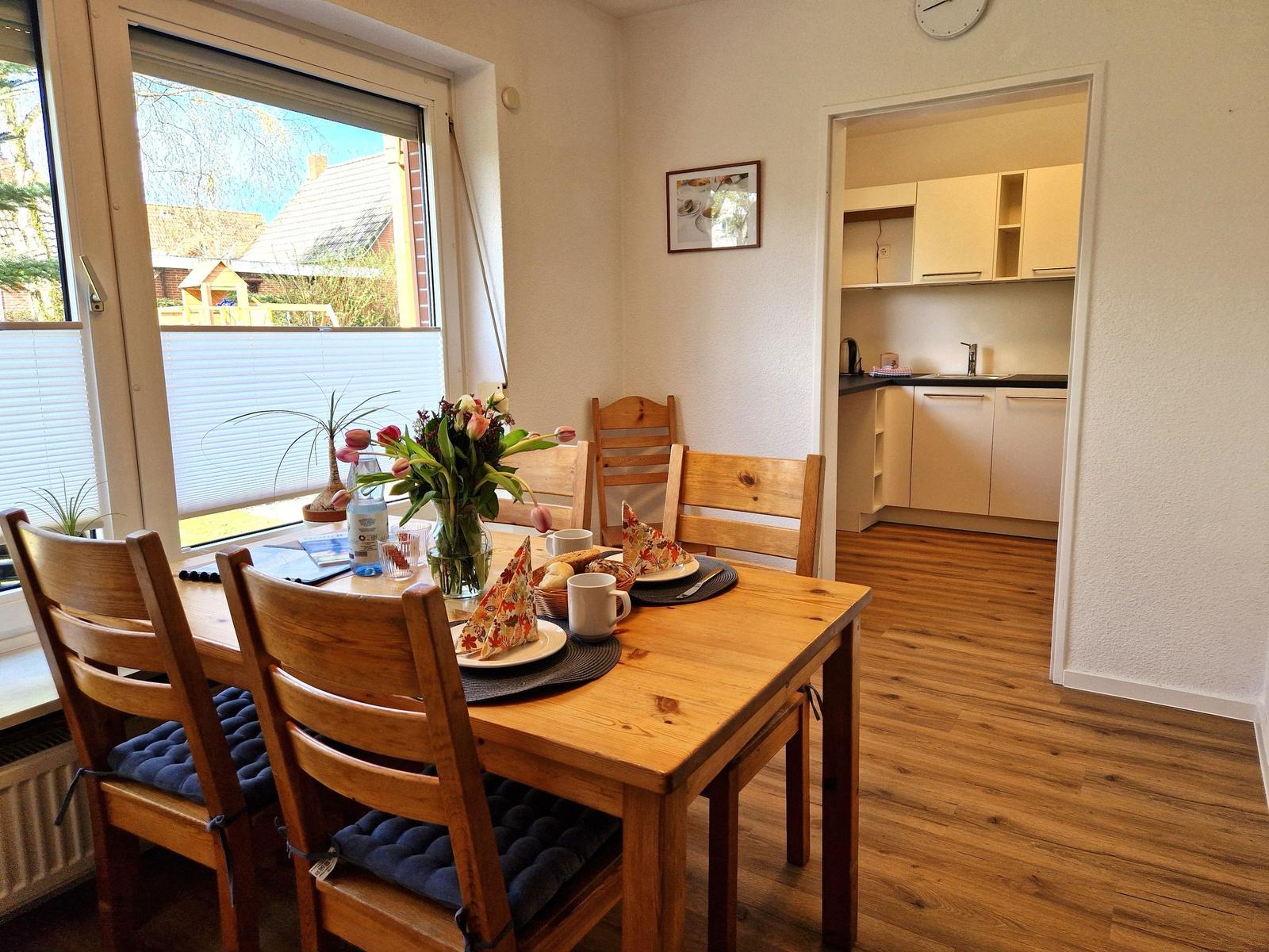 Esszimmer mit Holztisch, Stühlen und Blick auf die Küche.
