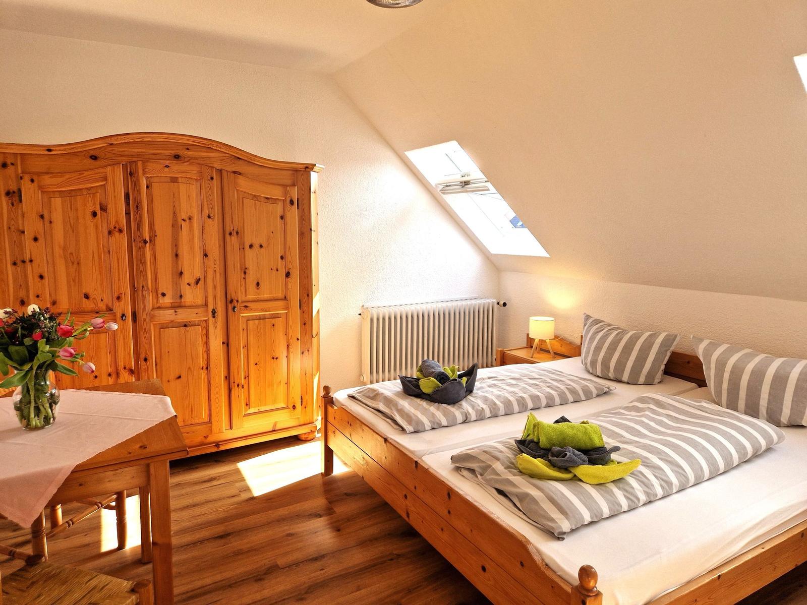 Doppelbett mit Streifenbettwäsche, Holzmöbel und Dachfenster. Holzfußboden und Kleiderschrank.