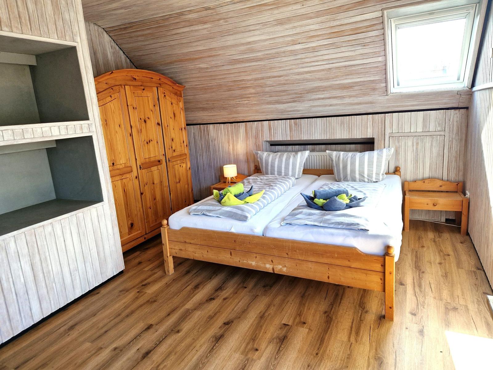 Schlafzimmer mit Doppelbett, Holzmöbel und Dachschrägen.