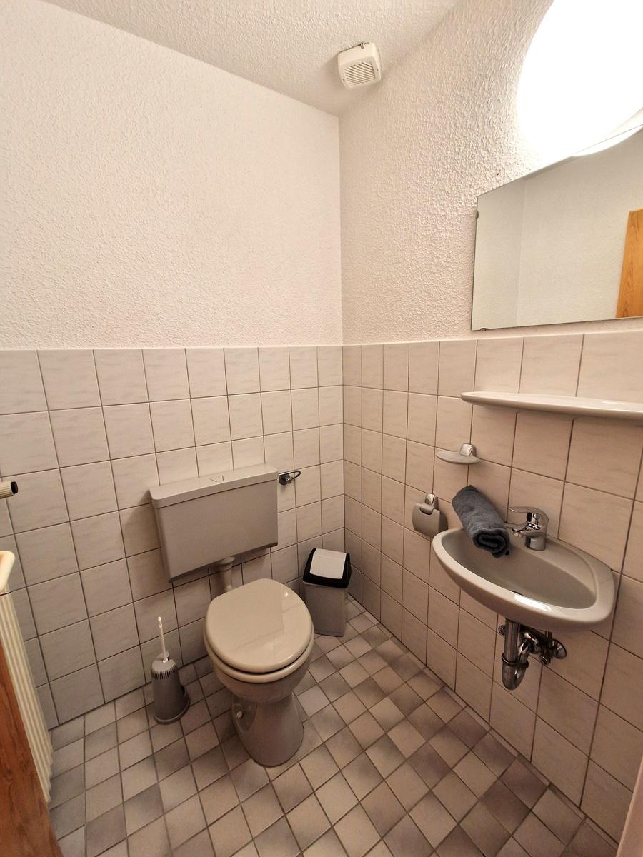 Badezimmer mit Toilette, Waschbecken und Spiegel an der Wand.
