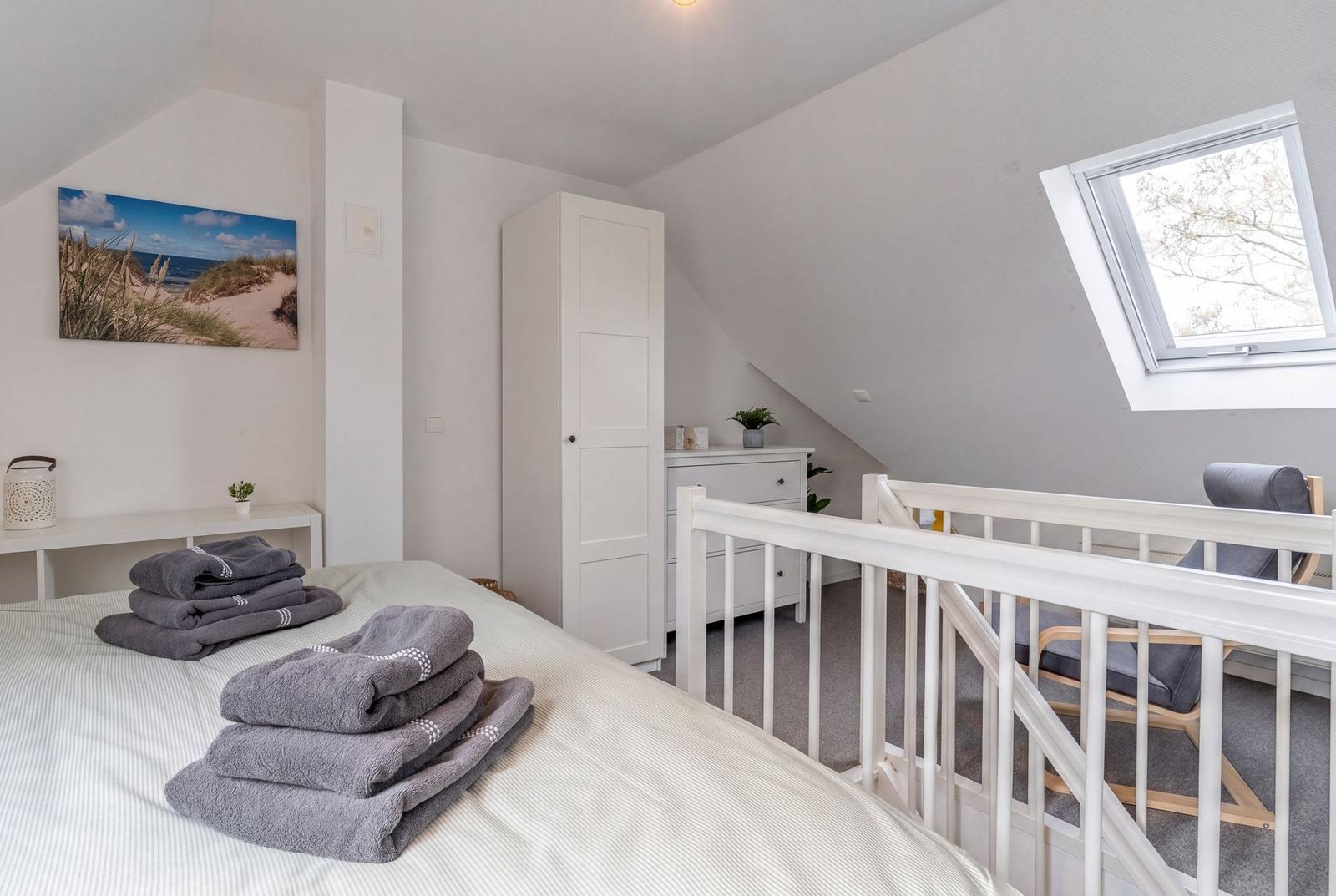 Schlafzimmer mit Dachschrägen, Bett, Kleiderzimmer und Dachfenster.