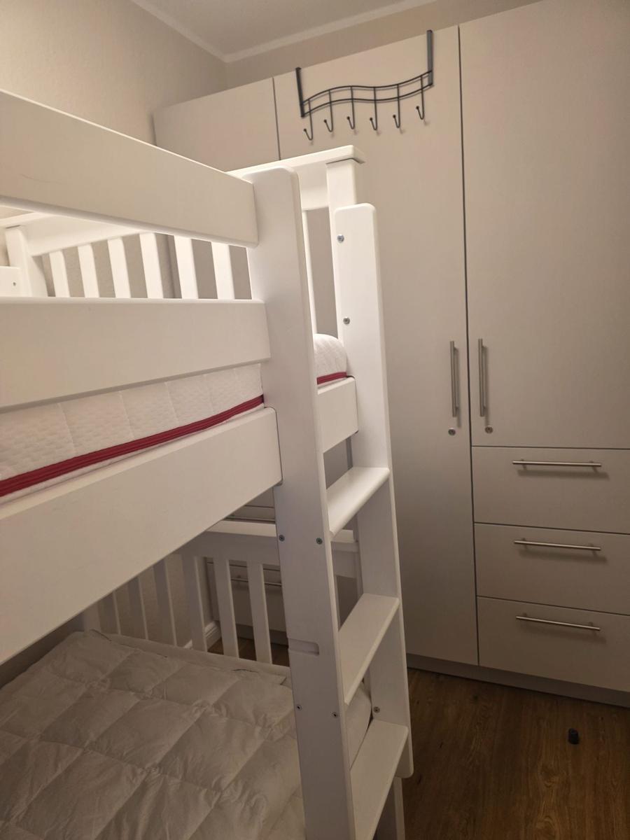 Zimmer mit Doppelstockbett und weißen Schränken mit Griffen.