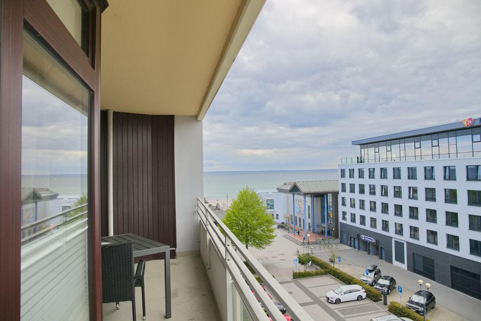 Balkon mit Tisch und Stühlen bietet Blick auf Meer und Stadt.