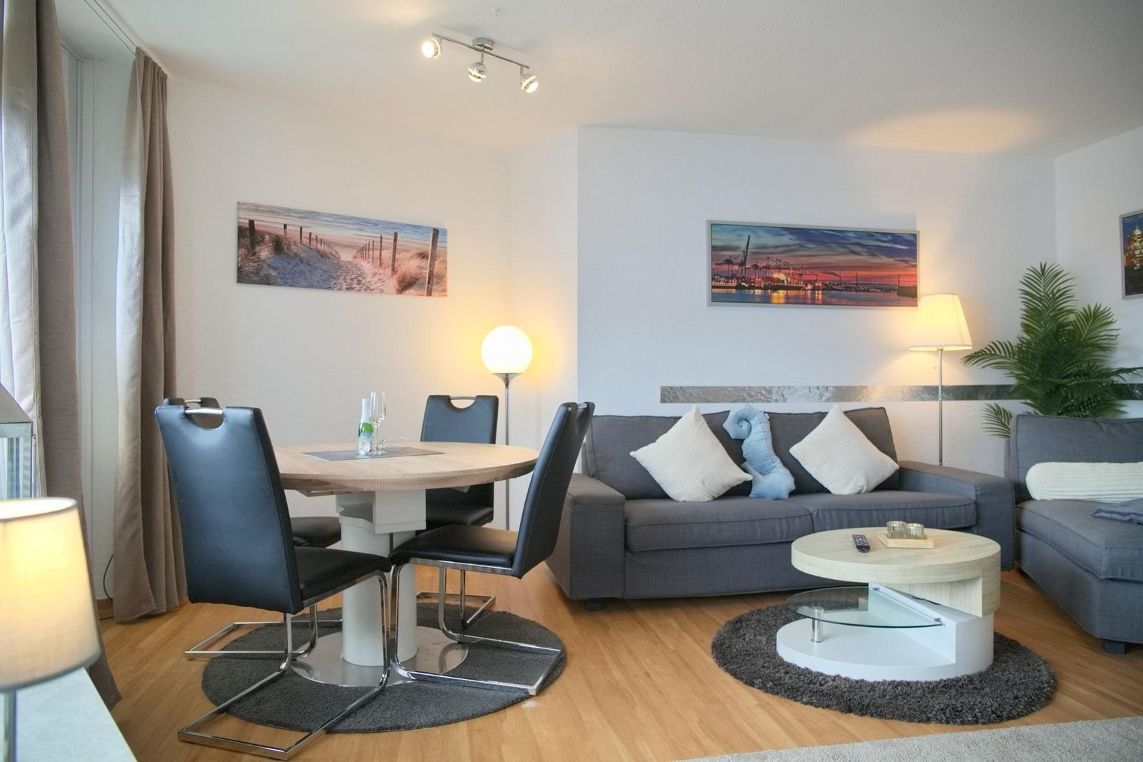 Wohn- und Essbereich mit Sofa, Esstisch und Wandbildern.