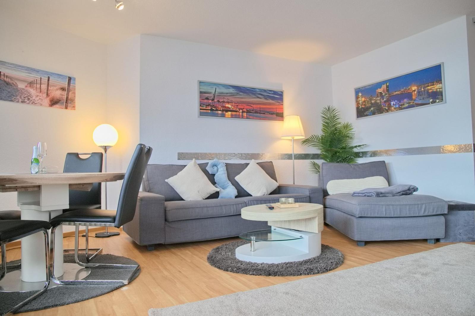 Wohn- und Essbereich mit Sofa, Tisch und Wandbildern.