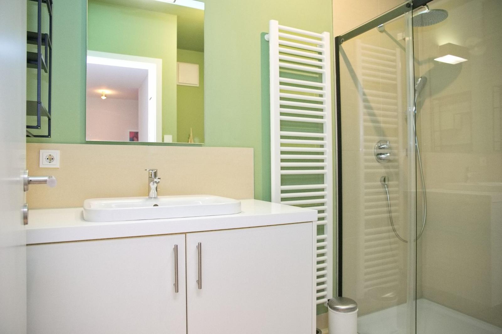 Badezimmer mit Dusche, Waschbecken und Spiegel