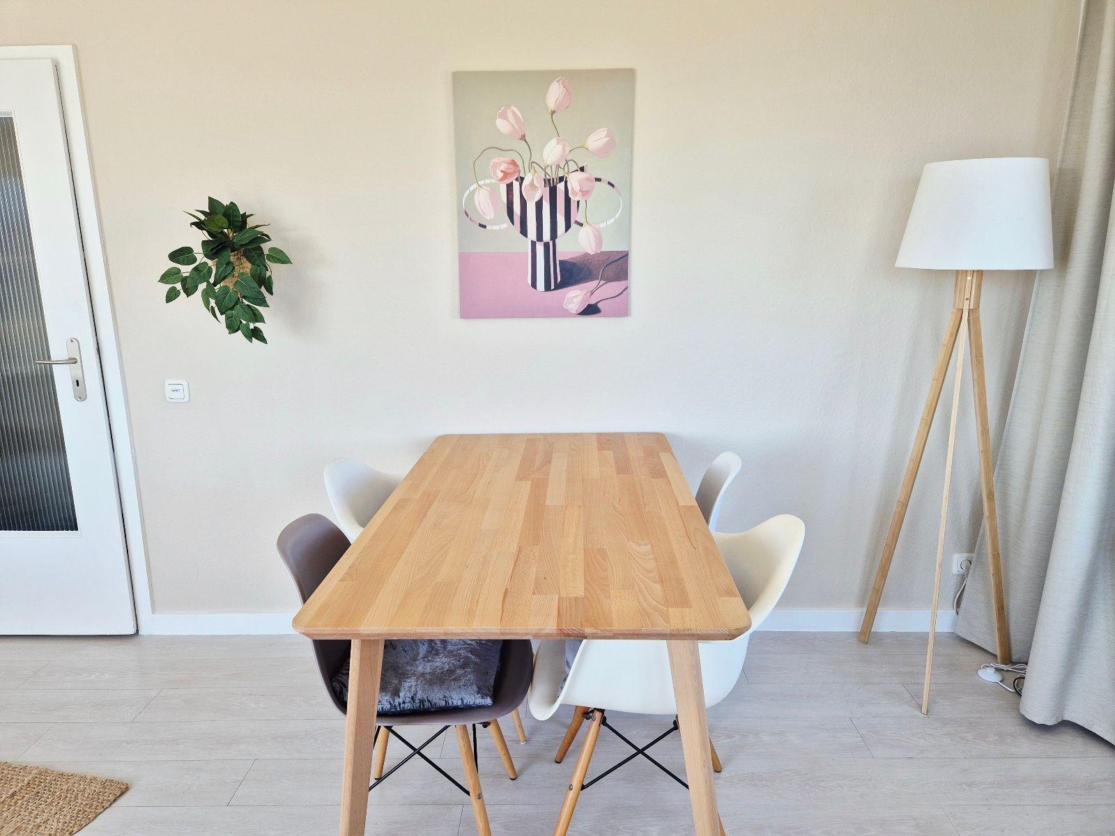 Esstisch mit Stühlen, Wandbild und Stehlampe im Esszimmer.