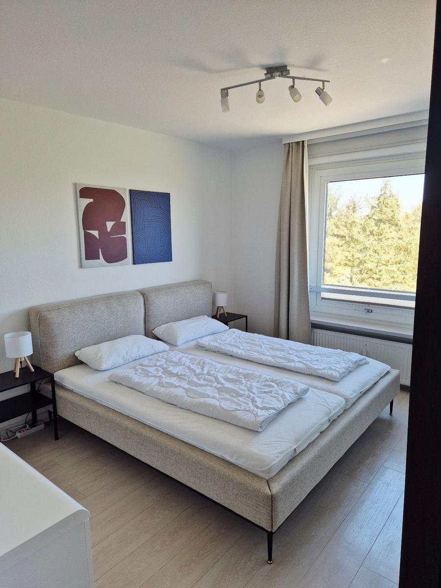 Schlafzimmer mit Doppelbett, Fenster und Wandbildern.