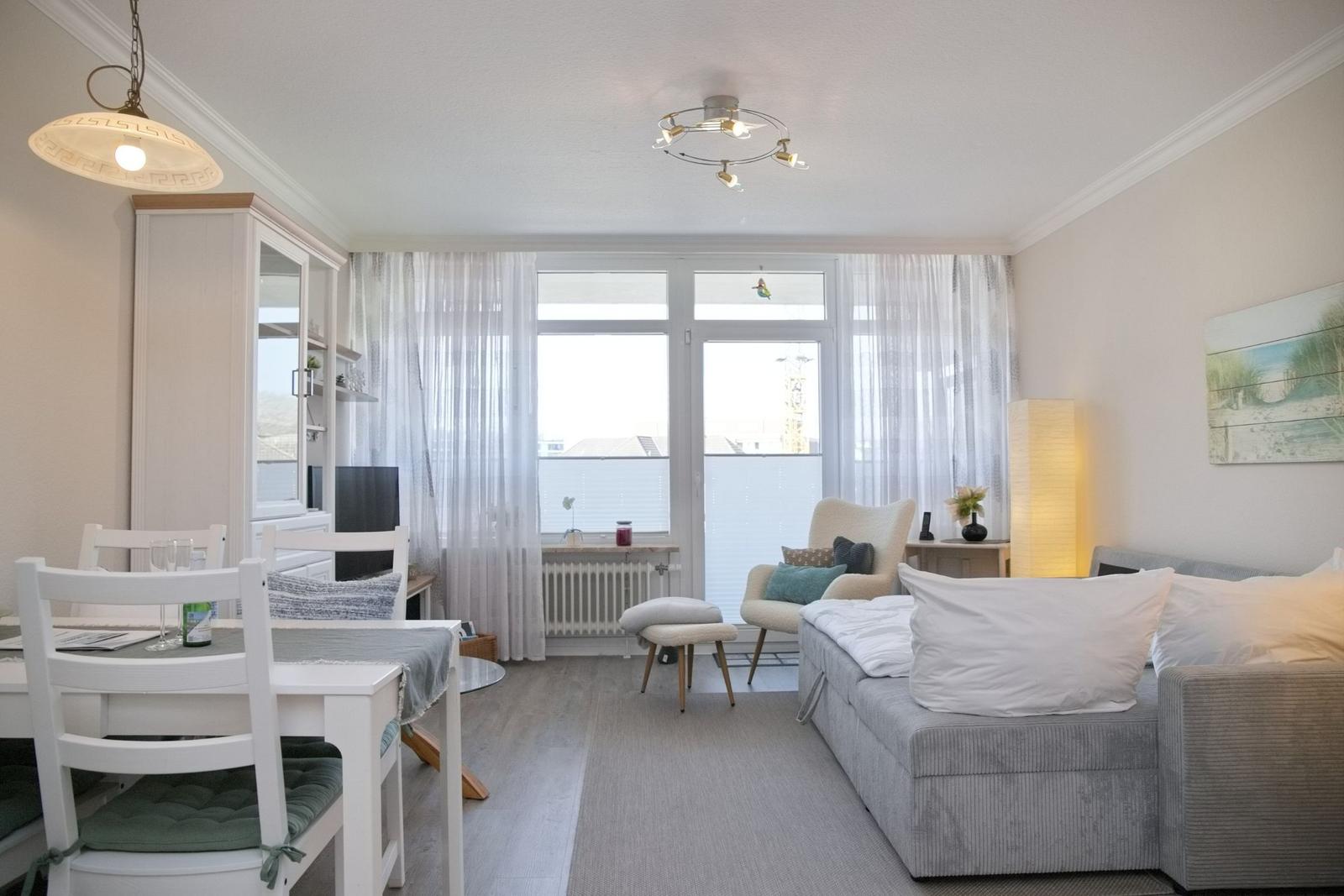 Wohn- und Essbereich mit Sofa, Stühlen und großem Fenster.