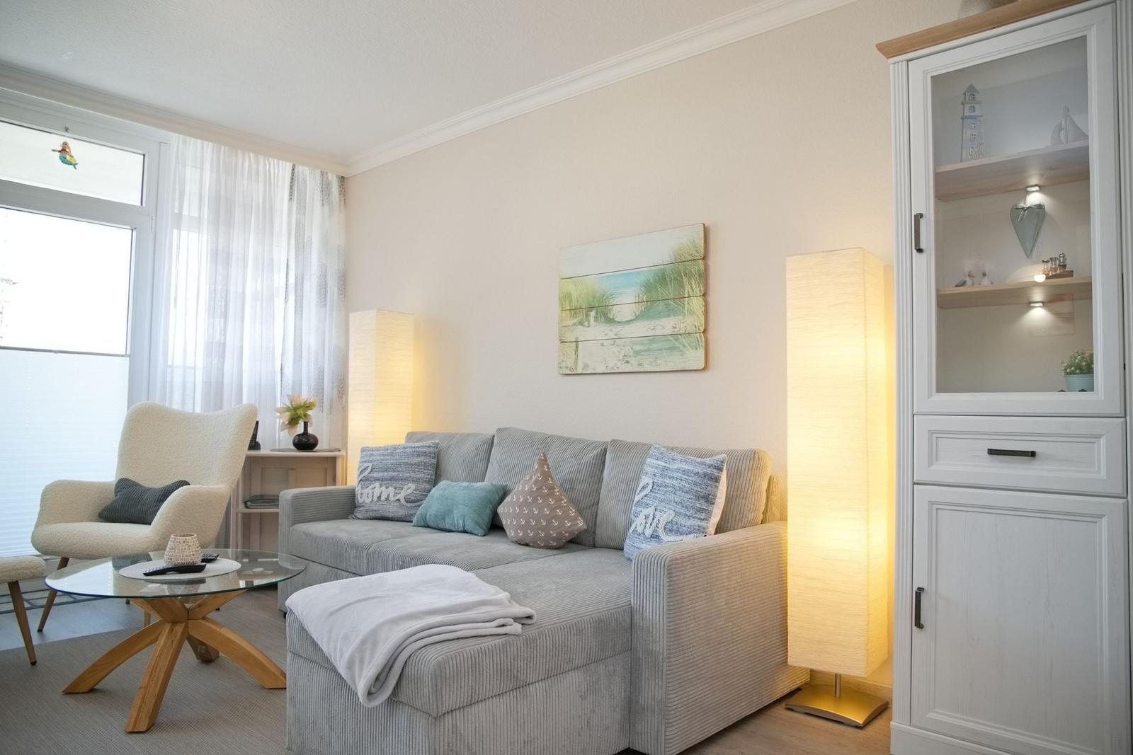 Wohnzimmer mit Sofa, Sessel, Beistelltisch und Vitrine.