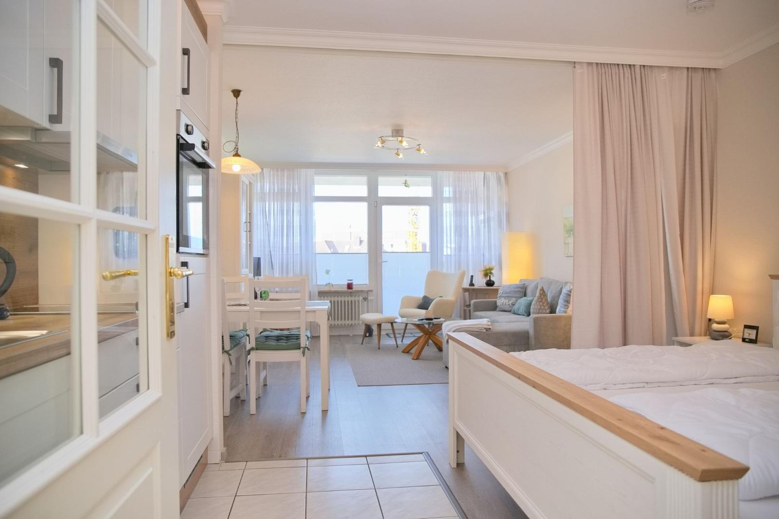 Schlafzimmer mit Bett, Wohnbereich mit Sofa und Essbereich mit Tisch und Stühlen.