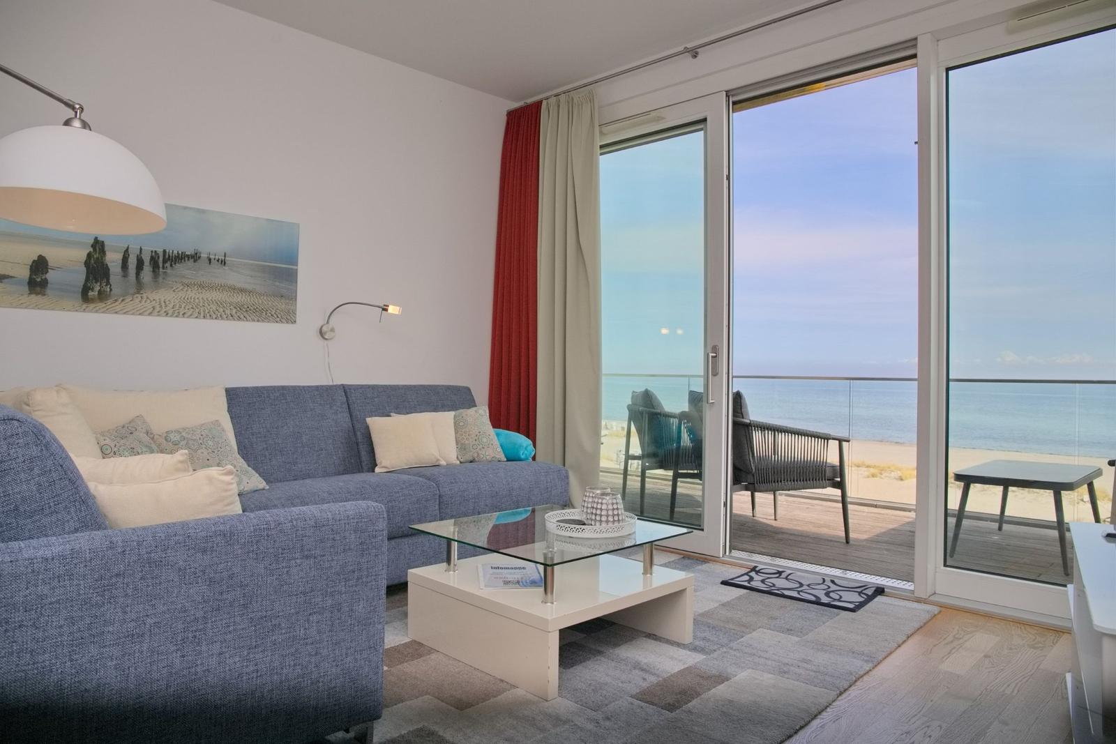 Wohnzimmer mit Sofa, Couchtisch und Blick auf die Terrasse mit Meerblick.