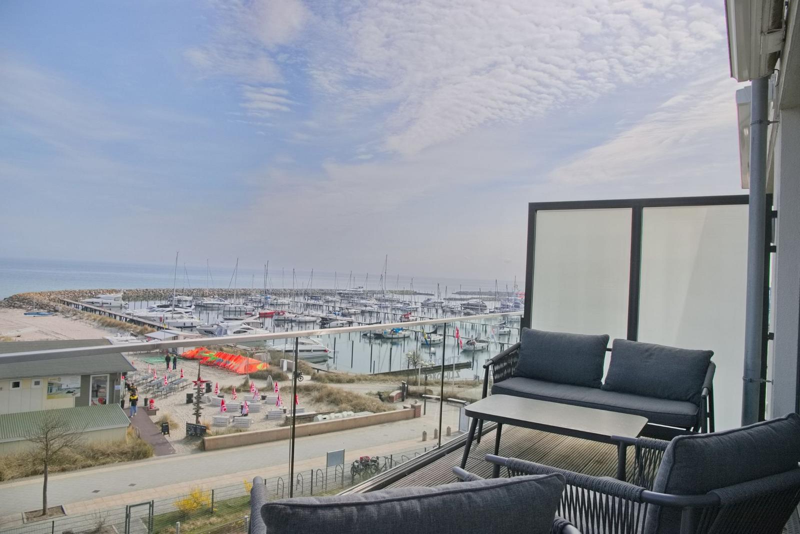 Terrasse mit Sitzgelegenheit und Blick auf Hafen und Strand.