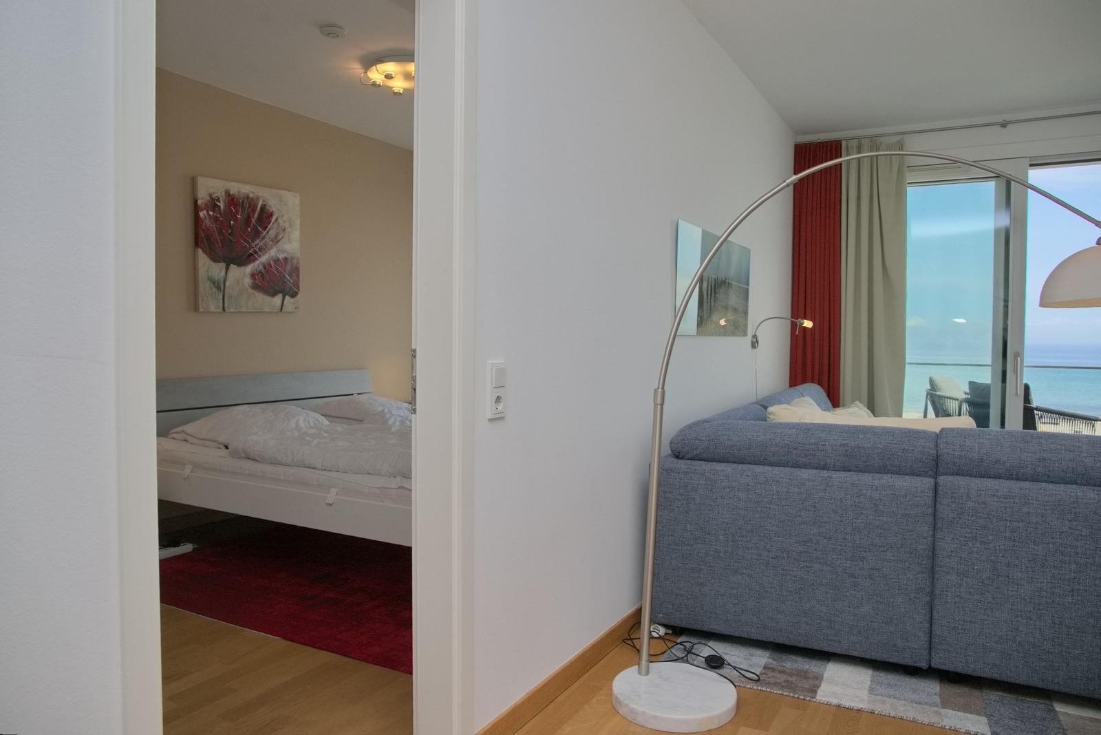 Wohnzimmer mit Sofa und Blick aufs Meer. Schlafzimmer mit Bett und Wandbild.