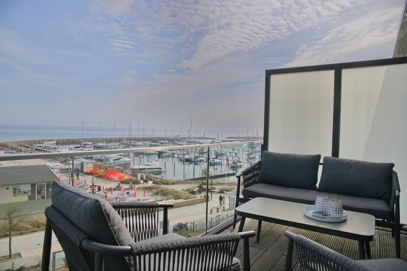Terrasse mit Sitzgruppe und Blick auf Hafen mit Booten.