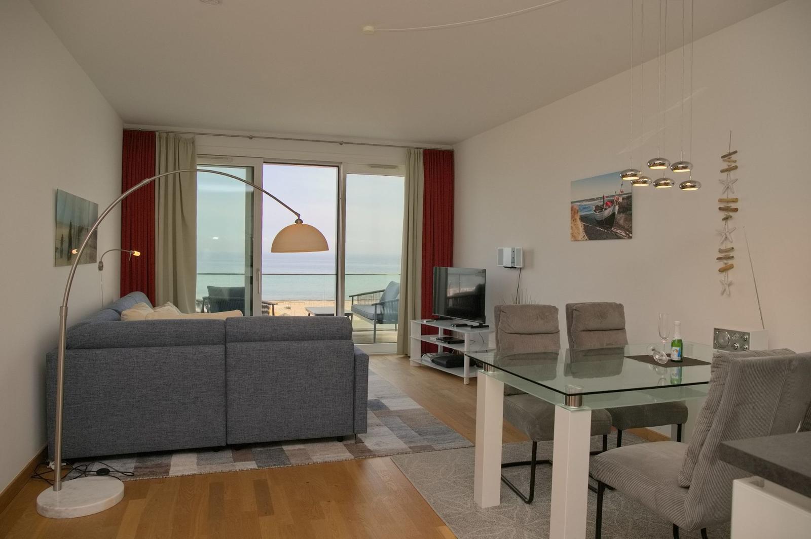 Wohn- und Essbereich mit Blick aufs Meer. Sofa, Esstisch und TV.