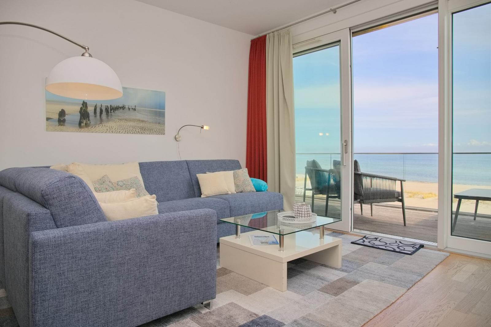 Wohnzimmer mit Sofa, Couchtisch und Meerblick über Balkon.