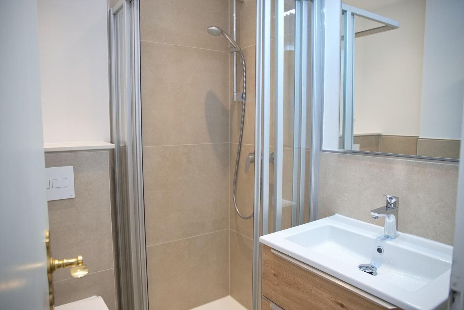 Bad mit Duschkabine, Waschbecken und Spiegel