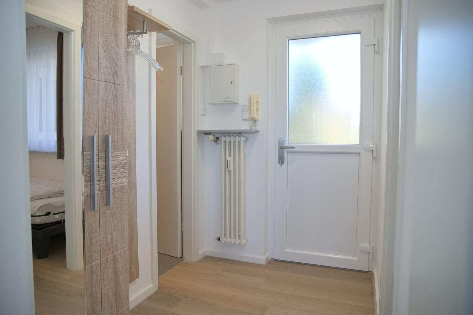 Eingangsbereich mit Kleiderschrank, Tür und Heizkörper an der Wand.