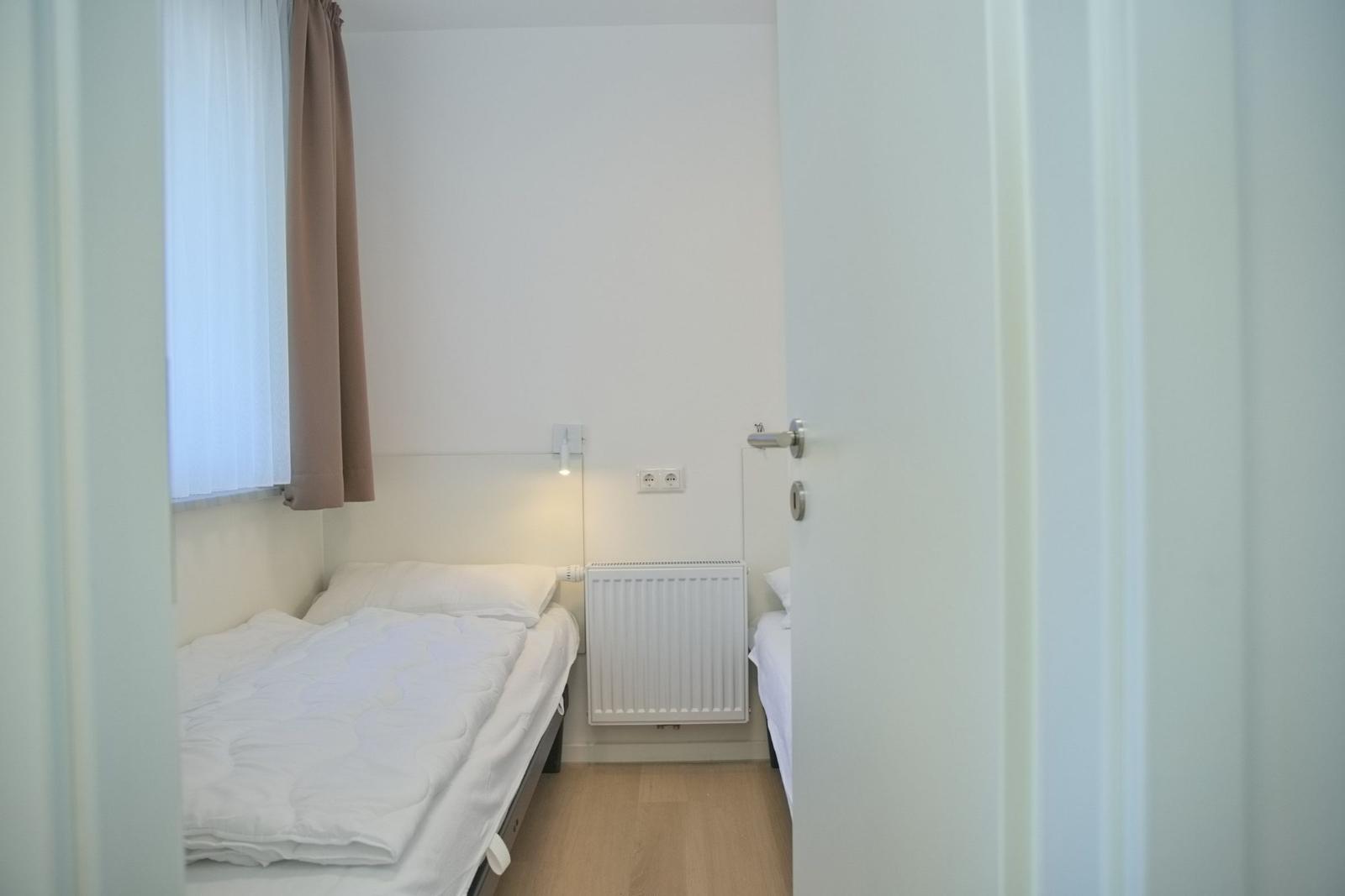 Ein Schlafzimmer mit einem Bett, einem Heizkörper und einem Fenster mit Vorhängen.