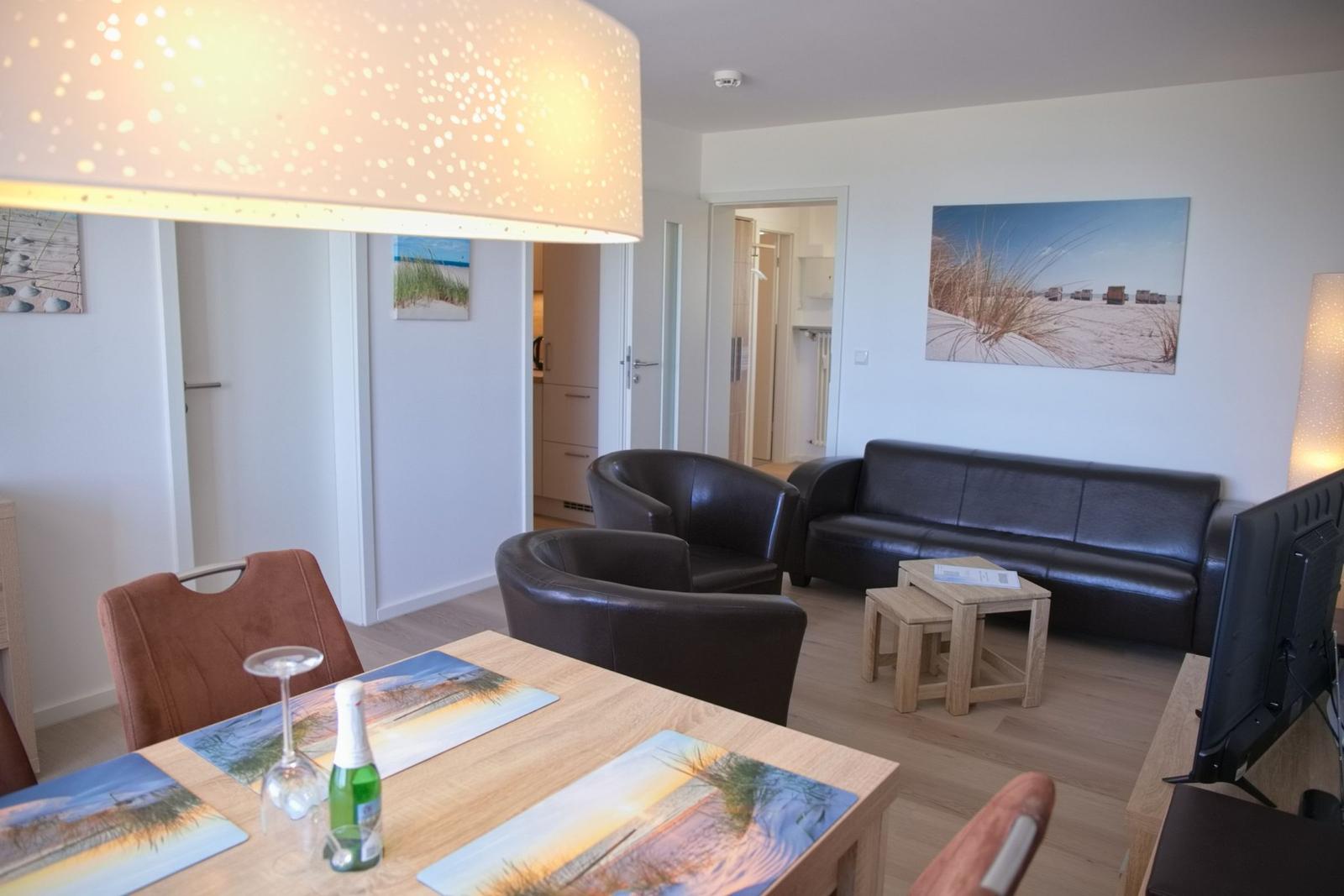 Wohn- und Essbereich mit Sofa, Stühlen und Tisch. Wandbild zeigt Strand.