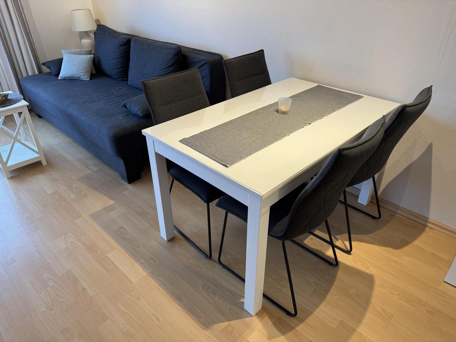 Esstisch mit vier Stühlen und Sofa im Wohnbereich.