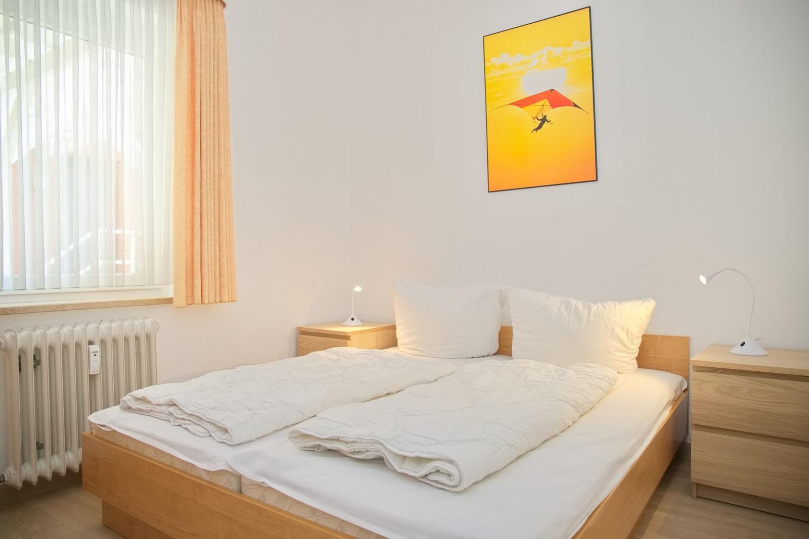 Schlafzimmer mit Doppelbett, Nachttischen und Wandbild mit Gleitschirm.