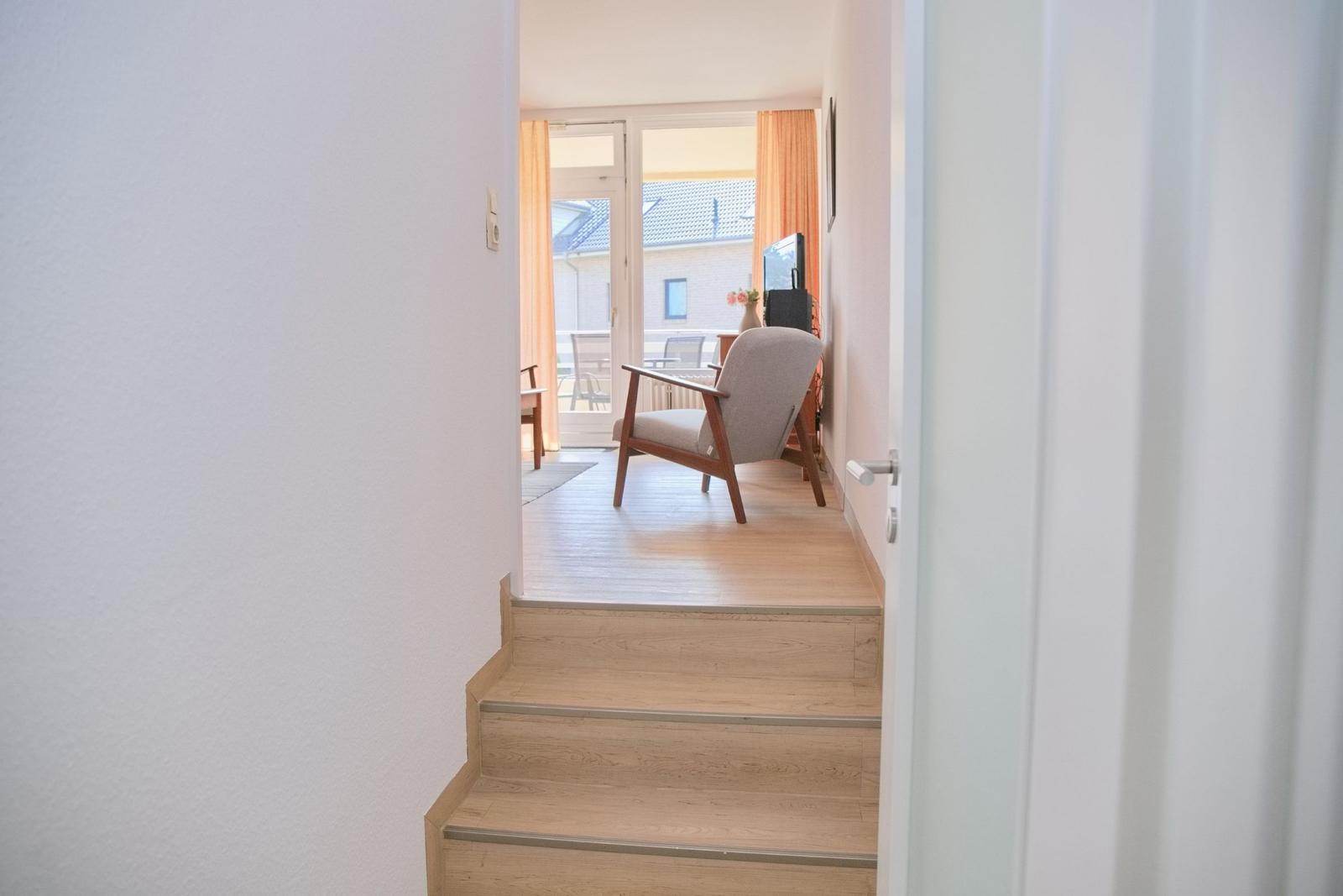 Haus mit Holztreppe und Sitzgelegenheit im Wohnbereich mit Blick auf Balkon.