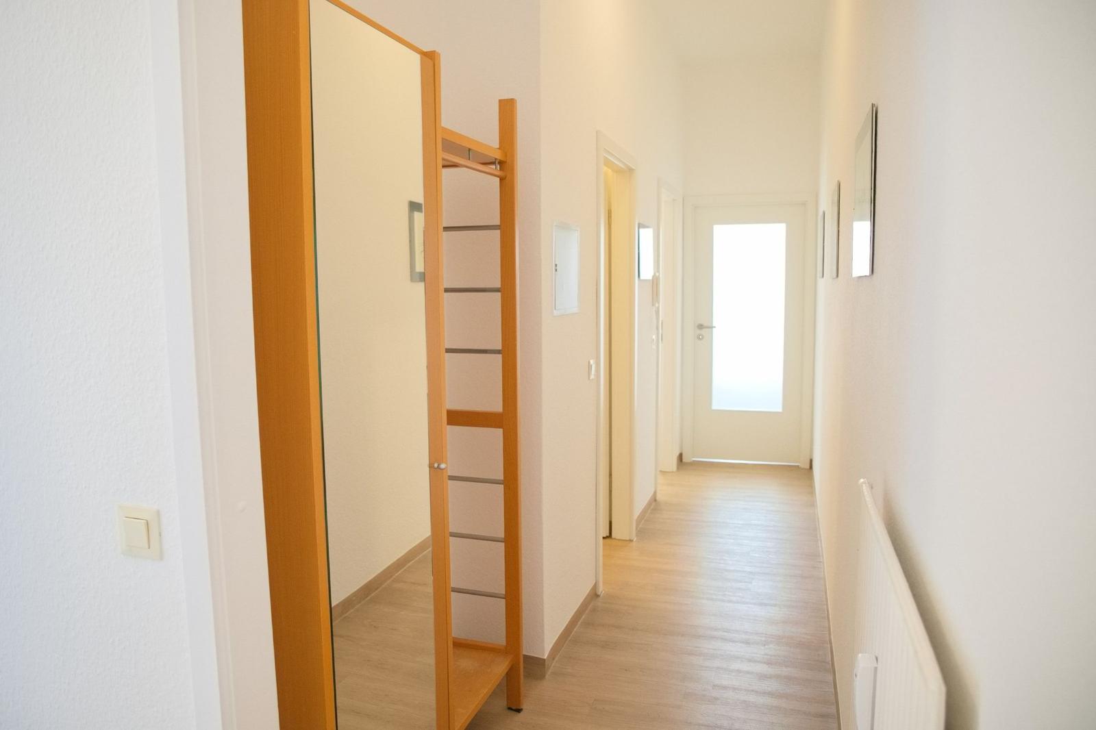 Flur mit Holzboden, Spiegelschrank und Türen zu Räumen