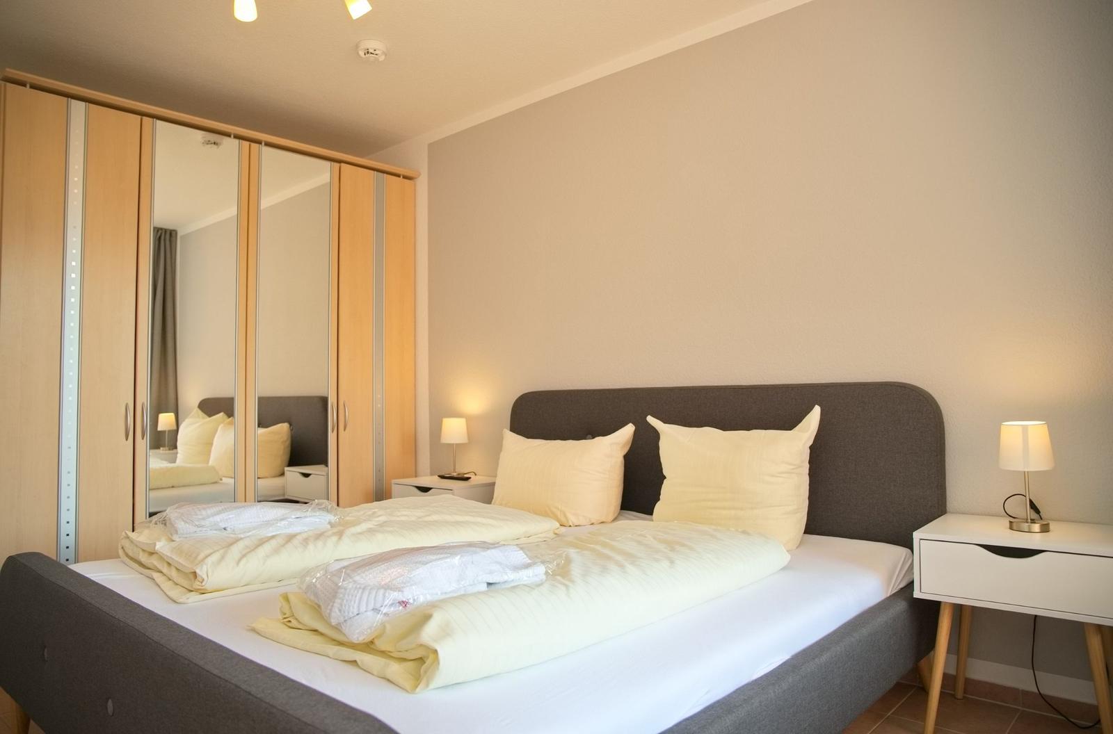 Schlafzimmer mit Doppelbett, Kleiderschrank und Nachttischen.