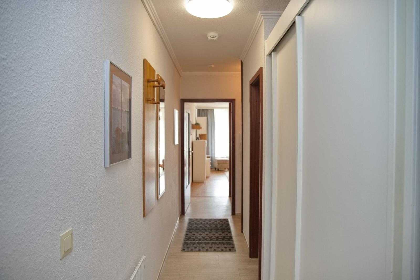 Flur mit Wandbildern, Teppich und Blick in Wohnbereich
