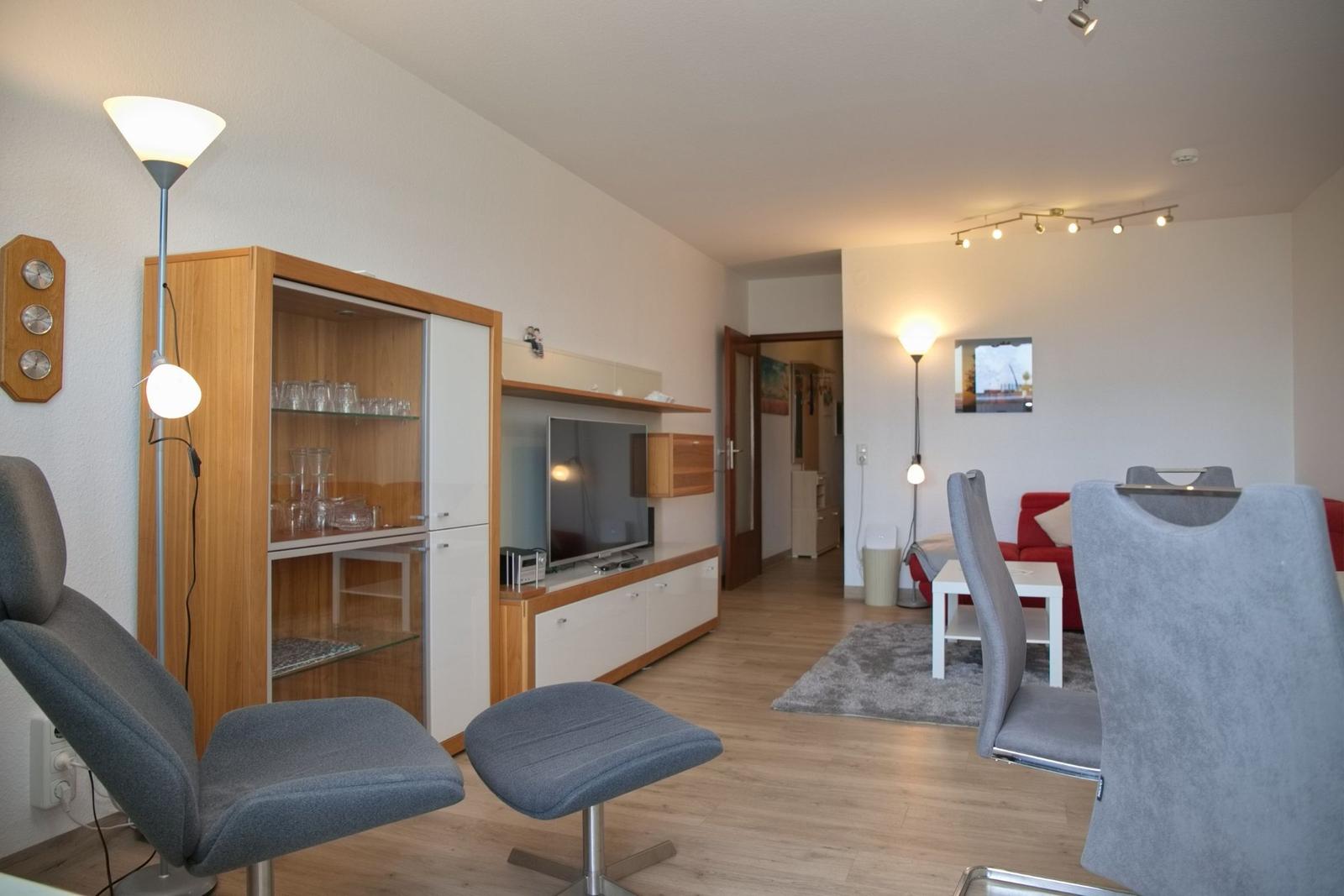 Wohnzimmer mit Essbereich, Fernseher und Glasvitrine. Holzboden und moderne Einrichtung.