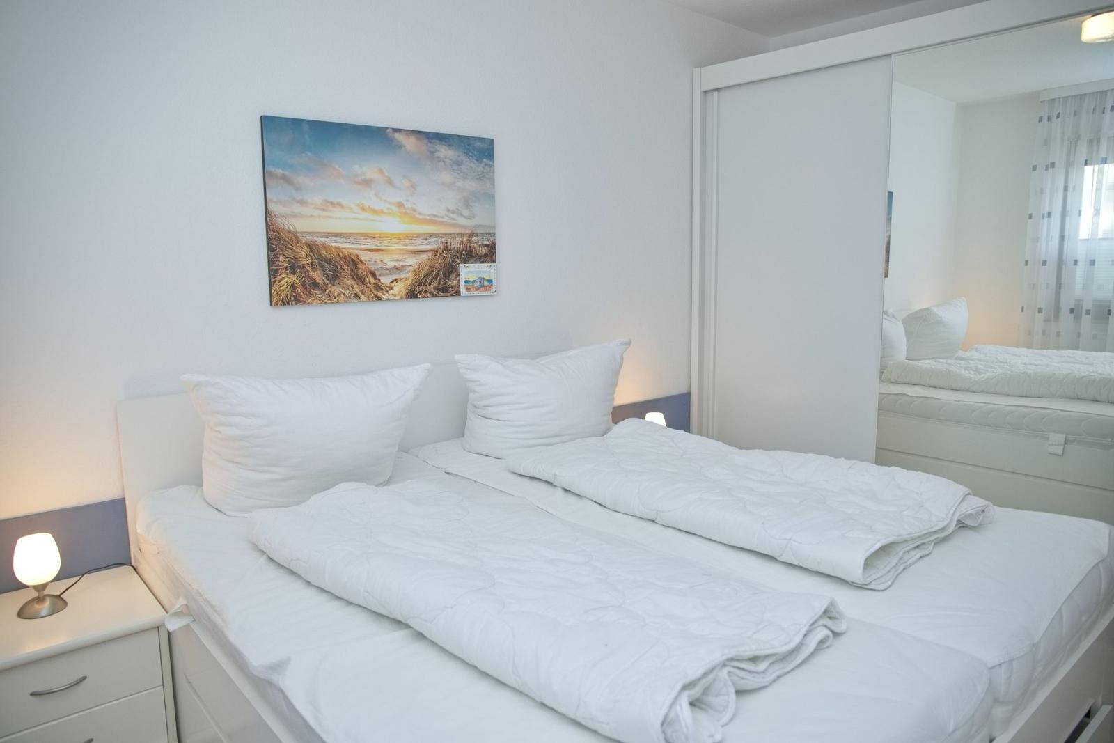 Schlafzimmer mit Doppelbett, Wandbild und Spiegeltüren.