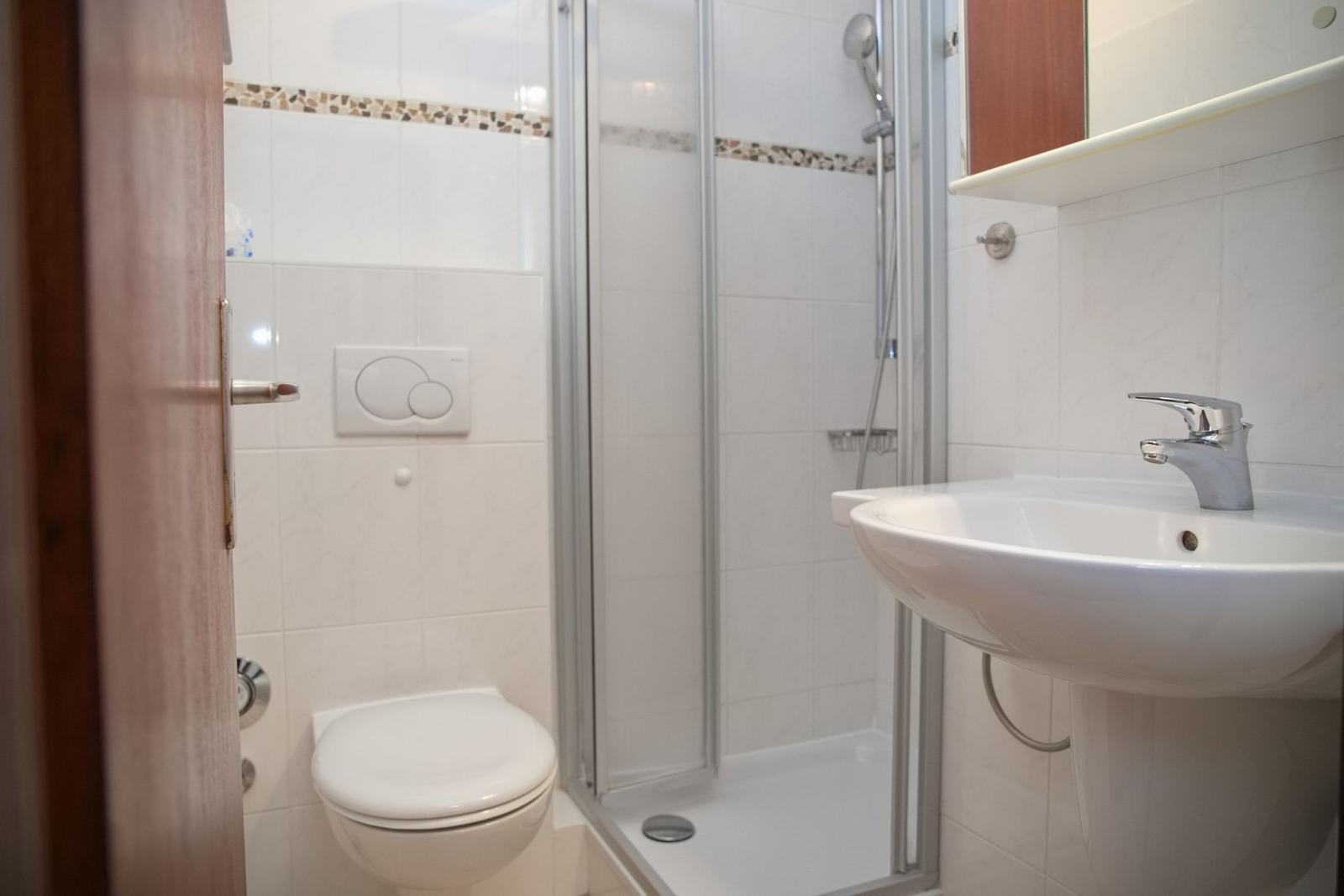 Badezimmer mit Dusche, Waschbecken und Toilette.