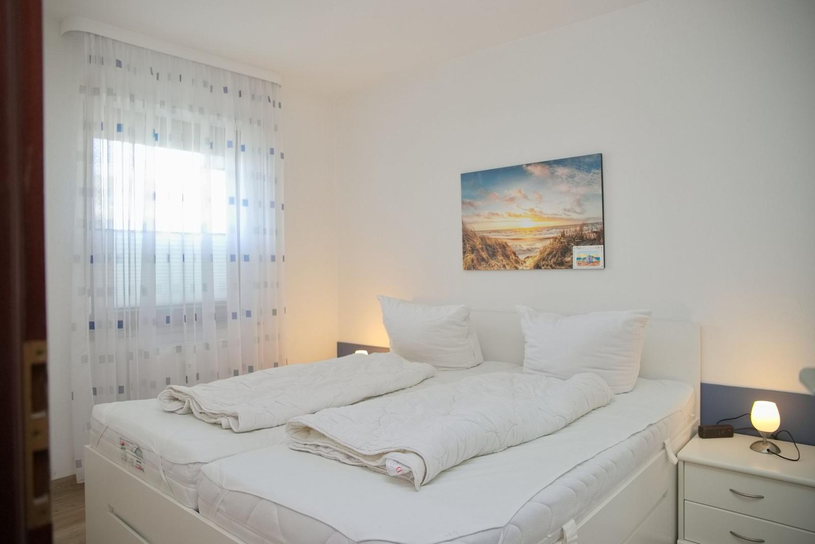 Schlafzimmer mit Doppelbett, Nachttisch und Wandbild an der Wand.