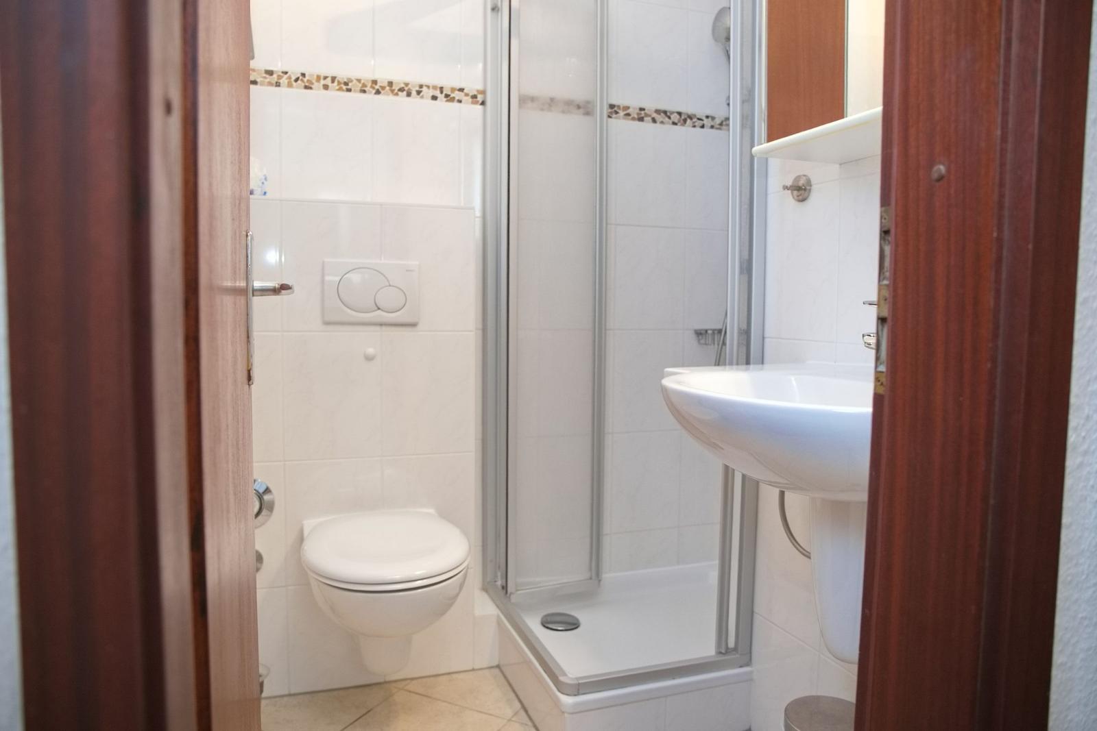 Badezimmer mit Dusche, Toilette und Waschbecken.