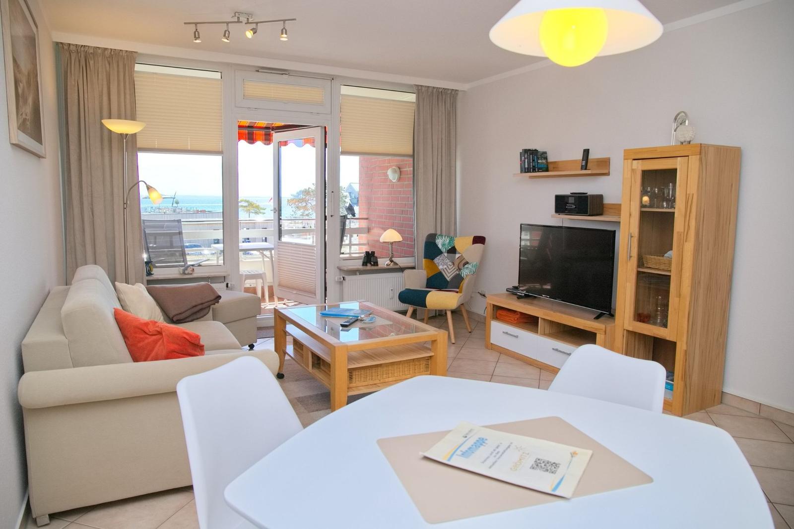 Wohnzimmer mit Sofa, Esstisch und TV. Balkon mit Meerblick.